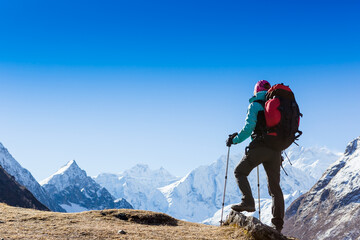 Woman Traveler with Backpack hiking in Mountains with beautiful Himalaya landscape on background...