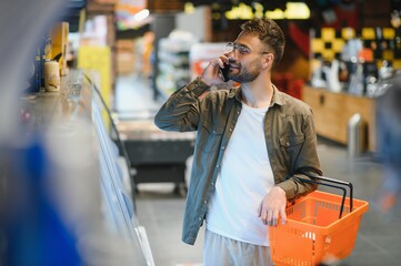 Handsome young man choosing food in the supermarket.
