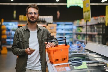 A handsome young man in a grocery store chooses food products.