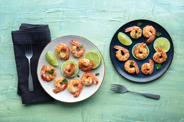 Shrimps at a restaurant, top shot on a teal blue table. Grilled shrimp with lime, spicy seafood dish