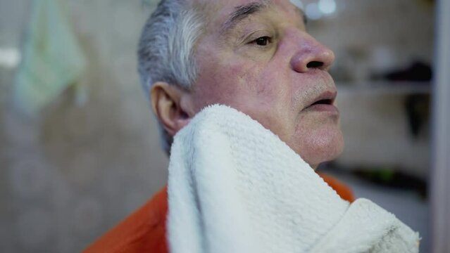 Close-up face of older man drying face post-wash routine in morning