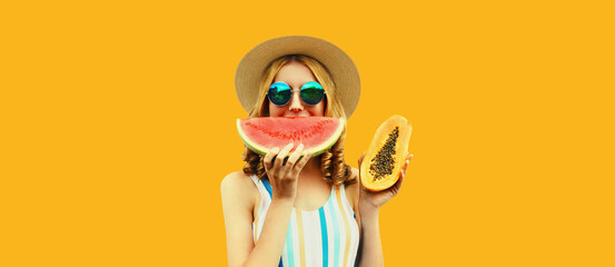 Summer portrait of happy woman eating fresh juicy slice of watermelon and papaya wearing straw hat,...
