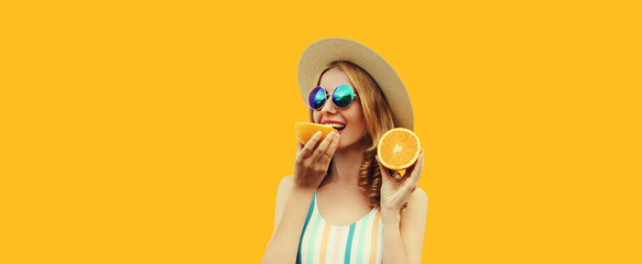 Summer portrait of happy young woman eating fresh juicy slices of orange fruits wearing straw hat,...