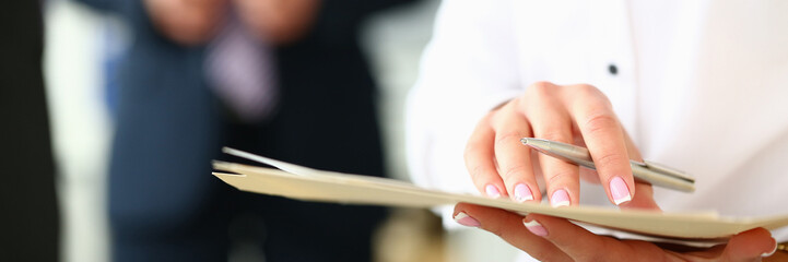 Women hands hold documents and pen against background of business people. Business meeting and successful work planning