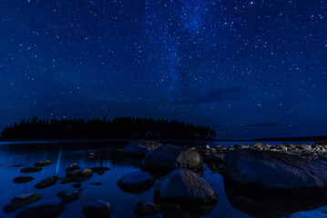 Astrophotography of landscape with a beautiful night starry sky and Milky way over water of sea...