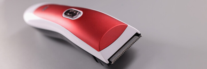 Red hair clipper on a gray background. Choosing a quality hair machine concept