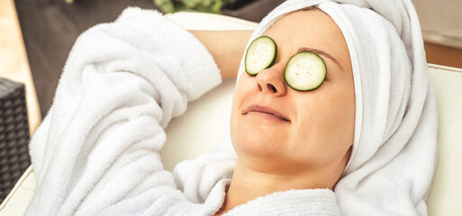 young woman getting eye nature treatment by cucumber at luxury spa resort. Wellness and healing concept.