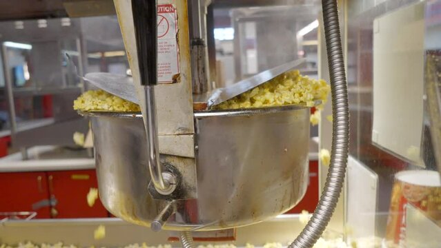AMC movie theater premiere hot popcorn cinematic slow motion overflowing out of machine mouth watering yellow buttery kernels hungry delicious tasting Hollywood circling to the left movement