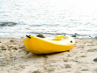 Obraz premium A yellow kayak boat on sandy beach and blue sea background with nobody, activity equipment prepare for hotel or resort guests on holiday summer vacation travel.