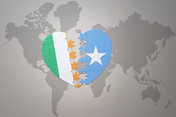 puzzle heart with the national flag of somalia and ireland on a world map background.Concept.
