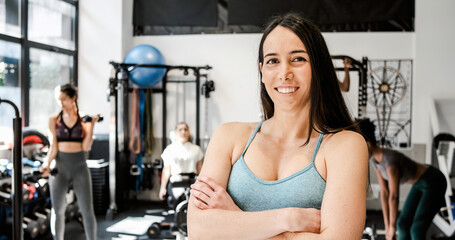 Fototapeta na wymiar Happy woman with folded arms in gym