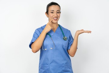 Funny Young doctor woman wearing blue uniform over isolated background hold open palm new product...