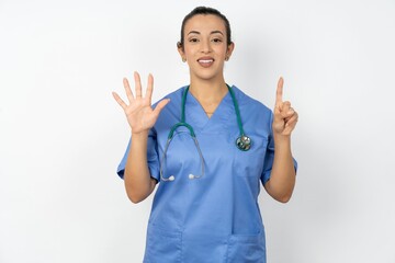 Young doctor woman wearing blue uniform over isolated background showing and pointing up with fingers number six while smiling confident and happy.