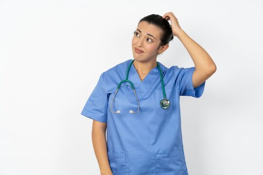 Young doctor woman wearing blue uniform over isolated background being confused and wonders about something. Holding hand on head, uncertain with doubt. Pensive concept.