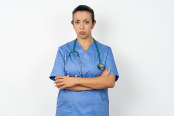 Gloomy dissatisfied Young doctor woman wearing blue uniform over isolated background looks with...