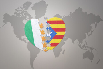 puzzle heart with the national flag of catalonia and ireland on a world map background.Concept.