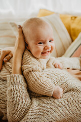 Newborn baby girl smiles and laughs on the bed. Orange and beige colors.