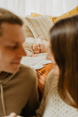 Fototapeta premium Young mother and father with their little daughter hugging and kissing on the bed.