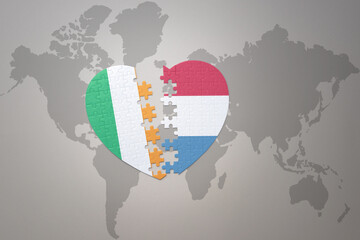 puzzle heart with the national flag of luxembourg and ireland on a world map background.Concept.