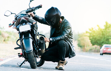 Motocyclist fixing the motorcycle on the road. Biker repairing motorcycle on the road, Man checking...