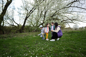 Mother with three kids in spring meadow.