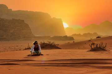 young woman playing in the sand of wadi rum desert at sunset