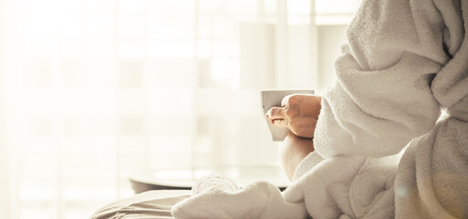 Woman in white bathrobe and towel lying on sofa and relaxing with tea at the roof.