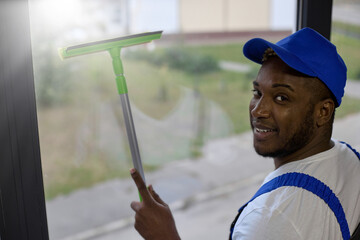 Experienced worker cleaning company with ease and smile copes with washing windows on upper floors....