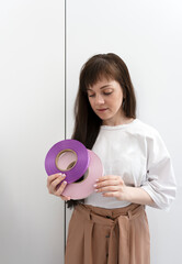 A female seamstress fashion designer tailor holding two coils of lilac and purple satin ribbon for labels or branding for clothing production.