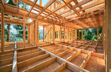 Under-construction residential wooden frame home located near a forest. Commencement of a new...