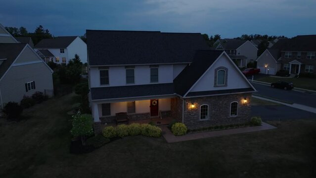Aerial descending shot of American home in USA during blue hour. Exterior lighting on dark night.