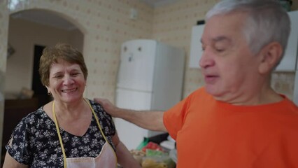 Older couple kissing in kitchen, wife kisses husband goodbye to start the day, senior couple peck kiss