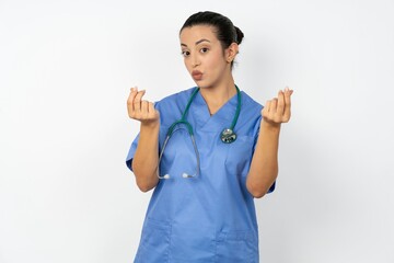 Beautiful doctor woman standing over white studio background doing money gesture with hands, asking for salary payment, millionaire business