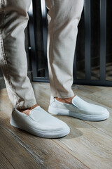 Plakat Male legs in leather summer shoes. Comfortable men's white moccasins without laces. Casual men's moccasins