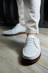 Male legs in leather summer shoes. Comfortable men's white moccasins without laces. Casual men's...