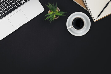 Laptop, coffee cups and notepads on a black background, top view.