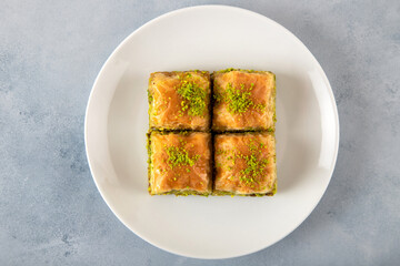 Pistachio Turkish baklava on a white plate.Close-up of four slices of baklava
