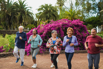 Group of fit senior people running together at city park - Multiracial elderly friends having fun...