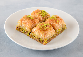 Pistachio Turkish baklava on a white plate.Close-up of four slices of baklava
