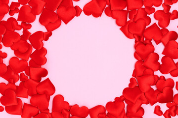 Round frame made of textile red confetti in a heart shape on a pink background. Copy space.