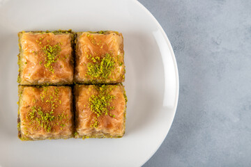 Pistachio Turkish baklava on a white plate.Close-up of four slices of baklava
