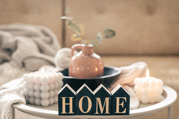 Cozy composition with decorative word home, candles and vase on blurred background.