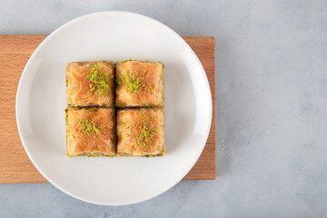 Pistachio baklava on a white plate.A plate baklava on light blue background