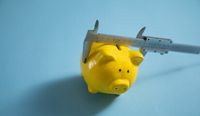 Piggy bank with vernier caliper on the blue background.