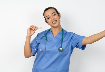 Beautiful doctor woman standing over white studio background make selfie holding an invisible...