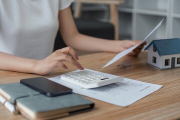 Young woman checking bills, taxes, bank account balance and calculating expenses in the living room at home