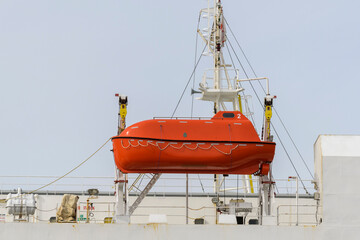 Lifeboat on big cargo vessel. Lowering orange lifeboat to water. Abandon ship drill. Lifeboat...