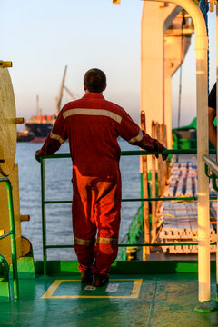 Seaman in red working overall and orange helmet on deck. Working at sea. Cargo vessel. Mooring operations. Able seaman.