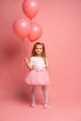 little girl in a white t-shirt and a pink tutu with balloons on pink background