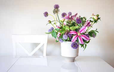 Vase with flowers from the garden in a white kitchen interior.